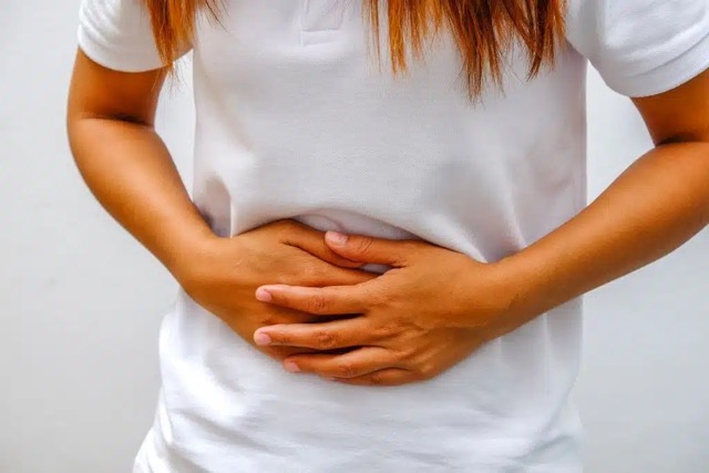 Femme souffrant de ballonnements liés à l'endométriose, les mains sur le ventre